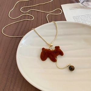 Detail of velvet puppy pendant on gold snake chain with a brown tiger eye stone bead