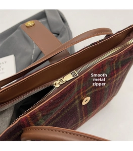 Detailed macro view of the gold-toned zipper and textured herringbone lining on woolen tote