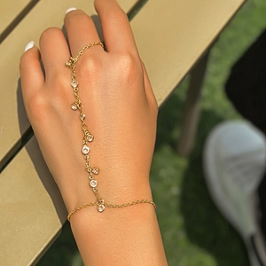 Detail of gold hand chain with rhinestone accents and faux pearls on a female hand