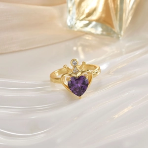 Close-up of golden crown ring with purple heart-shaped stone and micro-inlaid zircons