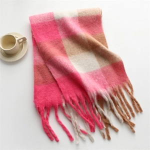 Close-up of pink and beige plaid scarf with soft tassels on a cozy white table