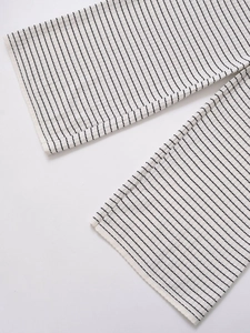 Détail du pantalon en tricot rayé noir et blanc montrant la texture côtelée et l'ourlet