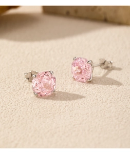Gros plan de boucles d'oreilles rose taille diamant avec monture argentée sur beige