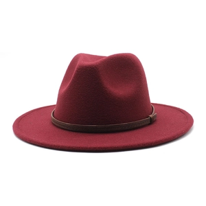 Detail of burgundy wool fedora hat featuring a brown leather decorative band and wide brim
