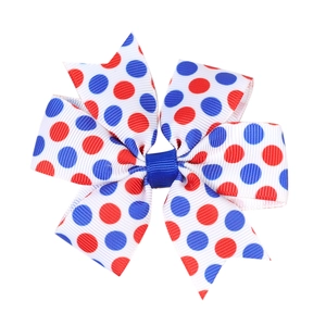 Close-up of red and blue polka dot grosgrain ribbon bow hair clip with textured fabric