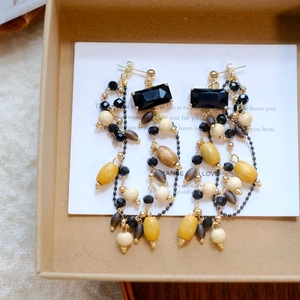 Macro detail of bohemian fringe earrings with wooden beads and black crystal on a card