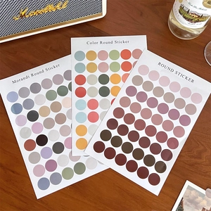Detailed view of Morandi round stickers on a wooden desk with decorative items