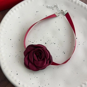 Macro shot of burgundy fabric rose choker with ribbon strap and silver metal clasp detail