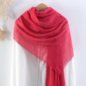 Detailed close-up of pink crinkled cotton scarf featuring elegant frayed tassel edges