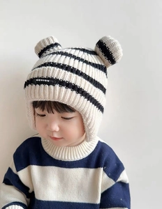 Detailed close-up of baby winter earflap hat in cream and black stripes with bear ears