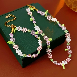 Detailed set of floral beaded necklace and bracelet on a dark green jewelry box