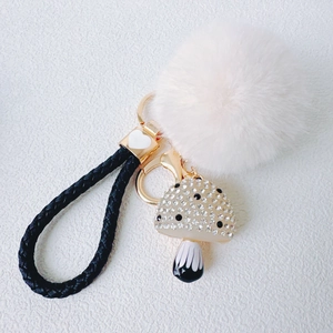 Detail of mushroom pendant with rhinestones, white faux fur pompom and woven leather strap