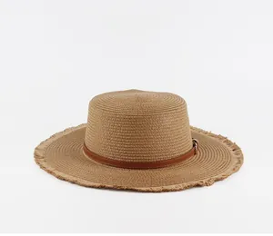 Close-up of tan straw boater hat with leather band and natural frayed brim details