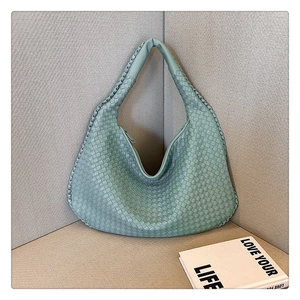 Close-up of light green woven leather texture on a stylish French shoulder handbag