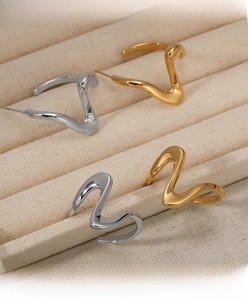 Detailed view of wave-shaped earrings in polished gold and silver finishes on a tray