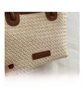 Detail shot of handwoven straw texture and premium brown leather stitching on bucket bag