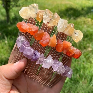 Close-up of three handmade hair combs with purple, orange, and yellow natural crystals