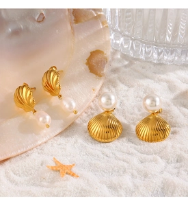 Detail van schelp- en hoorn-oorbellen met witte parels op zand voor de strandvakantie