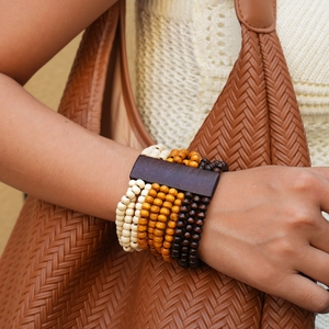 Macro detail of multi-layer wooden bead bracelet with geometric amber and cream beads