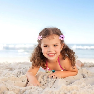 Detail of pink starfish and jellyfish hair clips for girls on beach background
