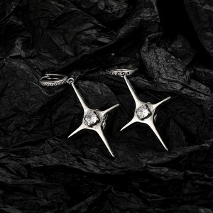 Minimalist silver four-point star earrings with white zircon on a black background