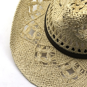 Détail du tissage floral ajouré sur chapeau de paille beige avec ruban en cuir brun