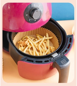 Close-up of brown air fryer paper liners holding fries and chicken inside the fryer basket