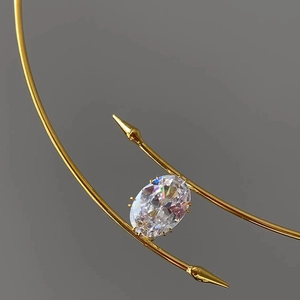 Gros plan du collier doré avec grand zircon ovale et monture en métal à pointes fines