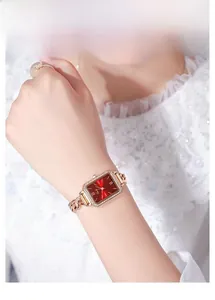 Detail of rose gold rectangular watch featuring a vibrant red dial and chain bracelet