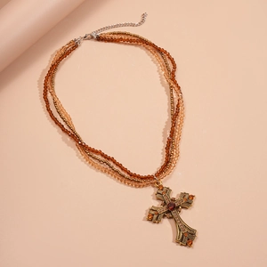 Detailed close-up of layered beaded necklace featuring a vintage rhinestone cross pendant