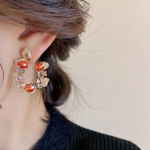 Close-up of C-shaped earrings with colorful gemstones and zircon on model