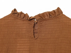 Close-up of brown ruched fabric with wavy collar and back button closure detail