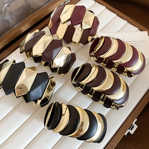 Detailed view of geometric beaded bracelets in gold, burgundy, and black in a jewelry box