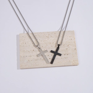 Polished silver and black titanium steel cross necklaces on stone pedestal display