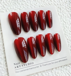 Vue détaillée des faux ongles œil-de-chat en amande longue couleur rouge vin brillant