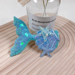 Close-up of glitter mermaid tail hair clip with starfish and seashell sequin details