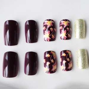 Short square press-on nails set with purple maple leaf designs and gold glitter finish