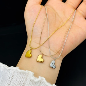 Close-up of heart pendant necklaces in gold, rose gold and silver finishes on hand