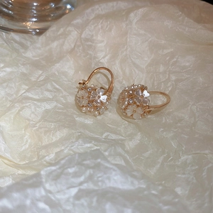Gros plan sur les boucles d'oreilles boule de fleurs dorées et détails en zircon