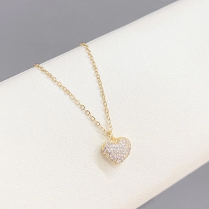 Elegant gold heart pendant necklace with shimmering cubic zirconia on white column