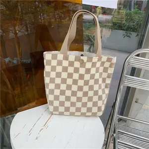 Detail view of checkerboard pattern tote bag with metal snap button closure and sturdy handles