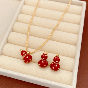 Detailed close-up of 18k gold-plated red gourd necklace and earrings in a beige jewelry box