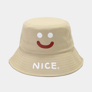 Detail of beige cotton bucket hat featuring a minimalist smiley face and NICE embroidery