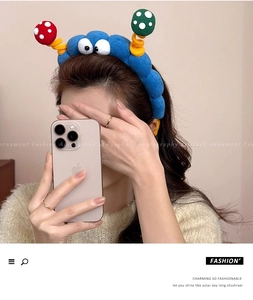 Close-up of blue plush headband featuring large cartoon eyes and colorful mushroom accents