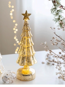 Detail of glowing mercury glass Christmas tree with gold star and warm LED light