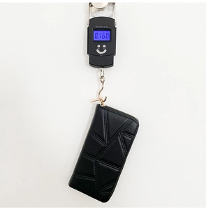 Detail view of a black quilted PU leather long wallet being weighed on a digital scale