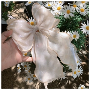 Close-up of a large champagne organza bow clip with a shimmering pearlescent finish