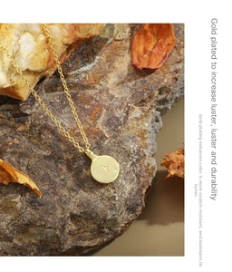 Detailed view of a gold-plated coin pendant with starburst engraving and zircon inlay