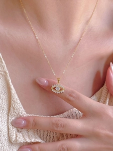Detail of 925 sterling silver eye necklace with gold plating and white zircon crystals