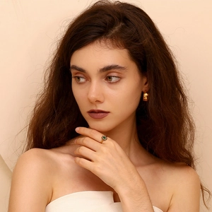 Detail of elegant gold flower ring with green gemstone and matching gold hoop earrings